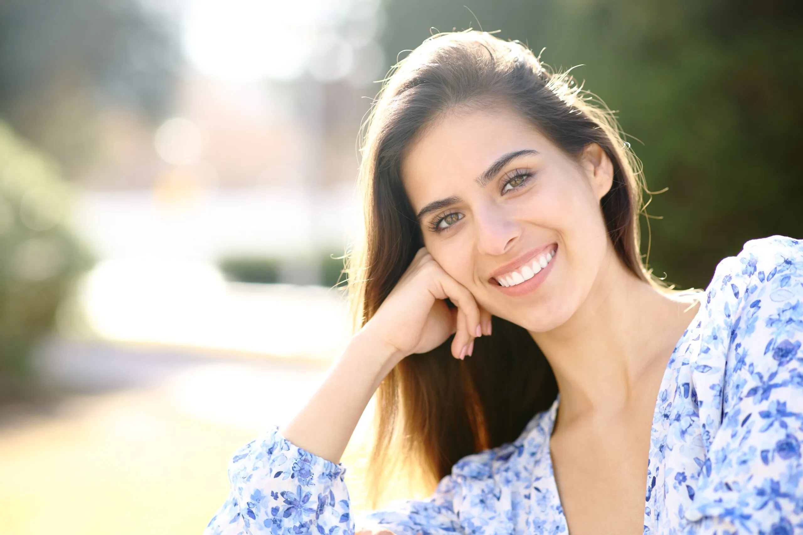 young woman in a park showing her flawless smile