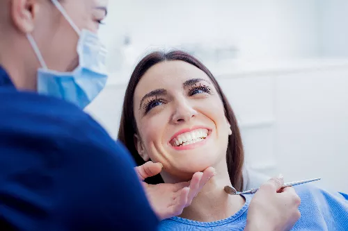 young woman smiling in a dental chair, showing off white teeth