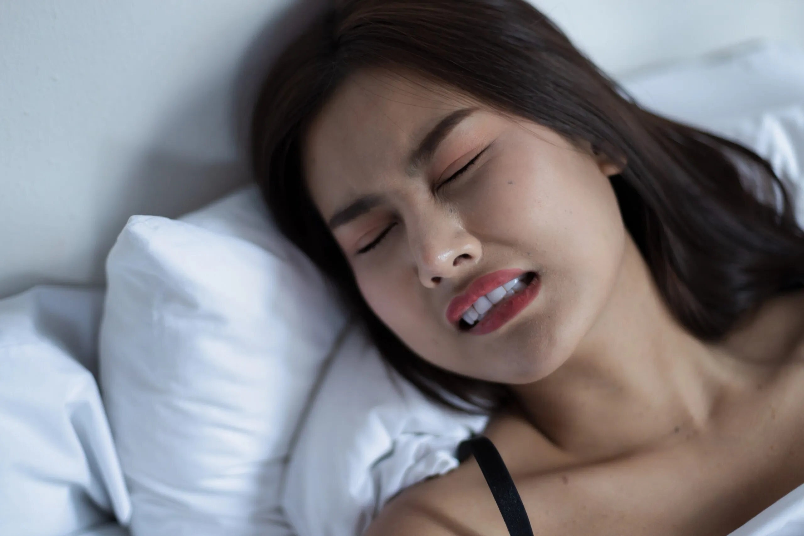 young asian woman grinding her teeth while sleeping
