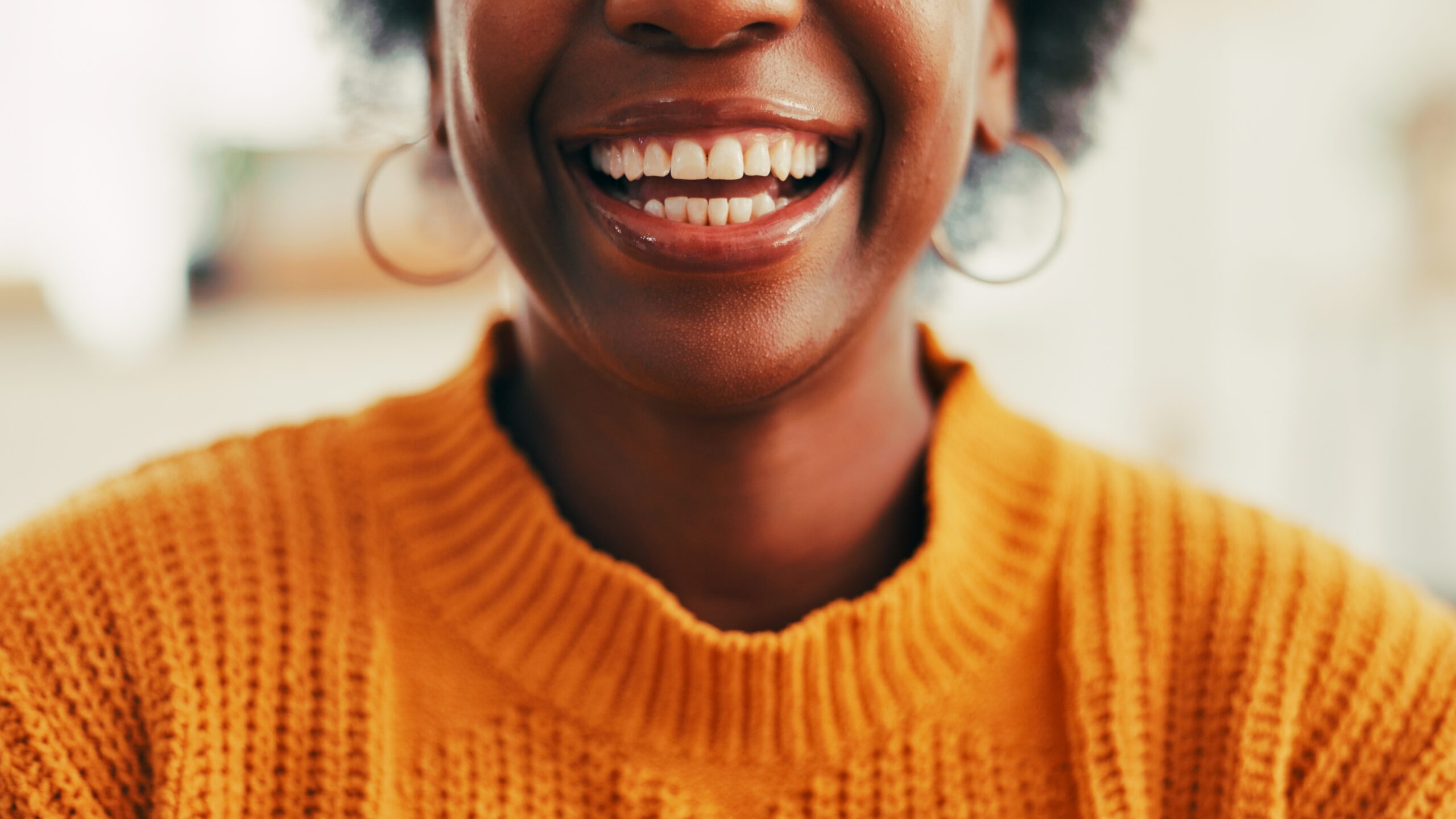 closeup of a smiling woman in a orange sweater, perfect white teeth